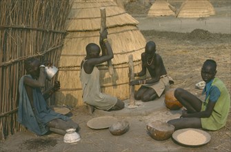 SUDAN, Agriculture, Dinka women pounding millet outside their hut.