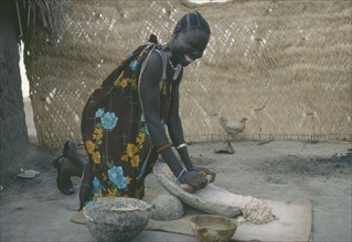 SUDAN, People, Shilluk woman grinding sorghum to make bread.