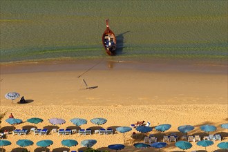 THAILAND, Phuket, Karen Beach, Sun umbrellars on golden sandy beach with boat at shoreline.