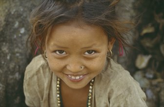 NEPAL, Dhankuta, Head and shoulders portrait of smiling young girl looking up to camera.