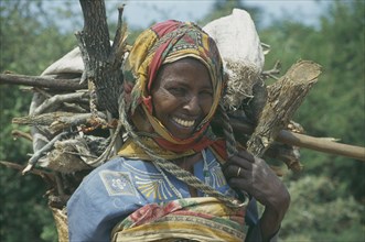 SOMALIA, Tribal People, Women carrying basket of firewood on her back near Baidoa.