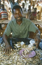 MALAWI, Mulanje, Portrait of male market stall holder selling dried fish. Able to do this due to