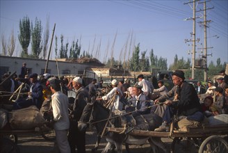 CHINA, Xinjiang Province, Kashgar, Busy street with crowds of men some traveling on donkey and cart