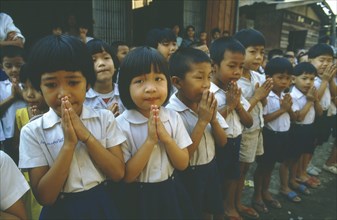 THAILAND, Tap Gaen, Line of school children giving traditional Thai greeting or wai with palms