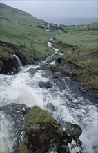 DENMARK, Faeroe Islands, River Gazadalla, Fast flowing rocky river with village and coastline