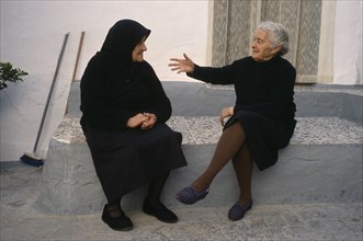 SPAIN, Andalucia, Two elderly ladies in conversation in village street.