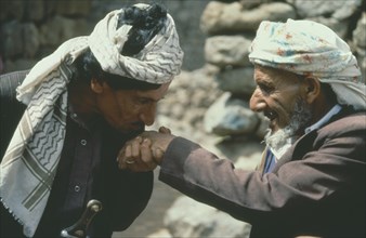 YEMEN, Jebel Aniz, Man kissing the hand of another in traditional Yemen greeting.