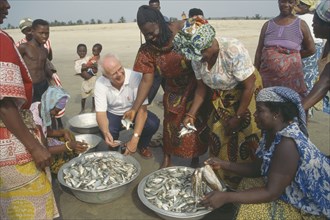 GHANA, People, Western man talking to women selling fish on beach near Accra.