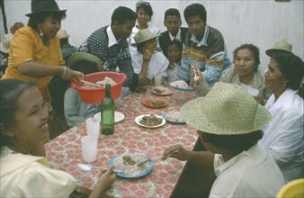 MADAGASCAR, Antananarivo, Large group of people having a meal of meat and rice.  Rice is a staple