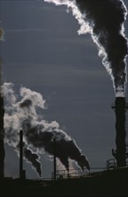 ENVIRONMENT, Pollution, Air, Smoke from industrial chimneys silhouetted against sun.
