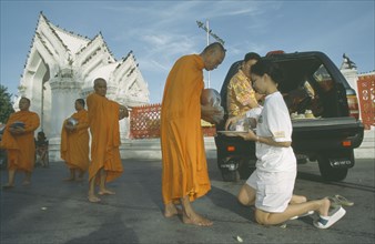 THAILAND, Bangkok, Monks collecting Alms outside Marble Temple. Wat Benchamabophit
