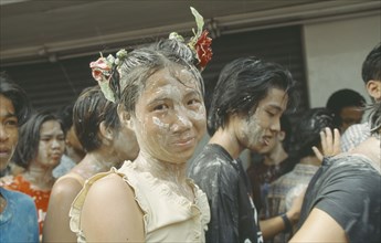 THAILAND, Bangkok, "Crowd covered in mud, young girl with flowers in hair,  celebrating the