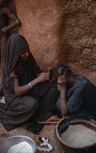 MAURITANIA, Oualata, Woman braiding the hair of another.