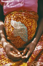GHANA, Volta Region, Cropped shot of woman thirty six weeks pregnant wearing brightly coloured