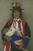 CHINA, Qinghai Province, Huzhu District, Tu minority Yellow Hat Buddhist woman carrying child