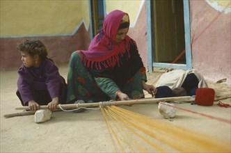 EGYPT, Western Desert, Mother and Daughter, Bedouin mother and daughter weaving on hand loom.
