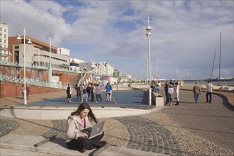 ENGLAND, East Sussex, Brighton, Woman using a laptop to surf the internet  in the free WiFi zone on