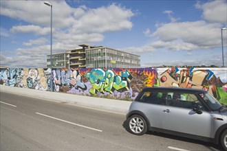 ENGLAND, East Sussex, Brighton, View across road with a Mini car traveling past towards a wall