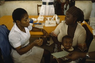 NIGERIA, Imo State, Medical, UNICEF vaccination project.  Female nurse with woman and crying child.
