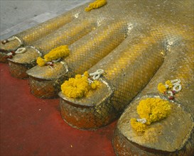 THAILAND, Bangkok, Banglamphu, Wat Indrawiharn. Close up of Floral offerings on the toes of a 45