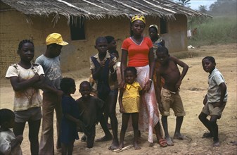 GABON, Family, Large family outside thatched building with mud brick walls.