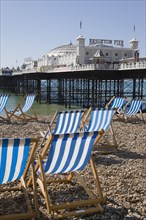 ENGLAND, East Sussex, Brighton, Brighton Pier with empty deckchairs on the beach in the foreground