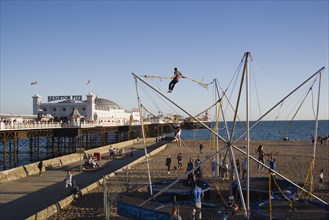 ENGLAND, East Sussex, Brighton, Brighton Pier and amusements on the beach with people  bouncing on