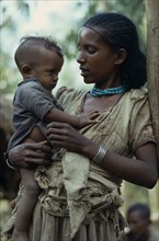 ETHIOPIA, Tribal People, Three quarter Portrait of young mother holding child.