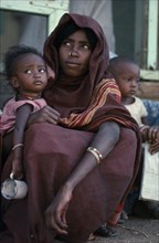 ETHIOPIA, Tribal People, Portrait of young mother with nose ring and facial scarification holding