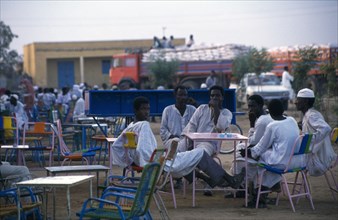 ERITREA, Tessanie, Group of men at outside tables of cafe in evening light.