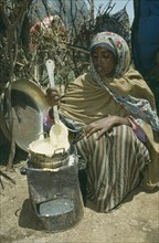 ETHIOPIA, Harerge, Jijiga, Ethnic Somali woman cooking porridge over fuel saving stove.