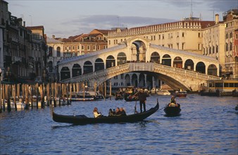 ITALY, Veneto, Venice, The Grand Canal and Rialto Bridge with gondola crossing in the foreground.