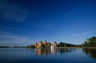 LITHUANIA, Trakai, "Wide angle view of castle reflected in lake with windswept clouds above,"