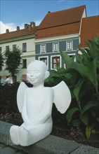 LITHUANIA, Vilnius, Moveable angel statue with typical buildings behind.