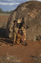 SOMALIA, Gedo, Woman and her two daughters outside their hut.