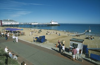 ENGLAND, East Sussex, Eastbourne, View from promenade across busy beachfront and pier.