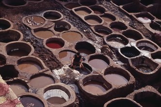 MOROCCO, Fes, Chouwara Tanneries.  Man working at the tanner’s pits.
