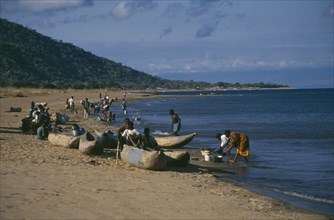 MALAWI, Lake Malawi, Cape Maclear with children playing on shore in wooden canoes and women washing