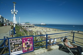 ENGLAND, East Sussex, Eastbourne, View from promenade towards beach and bandstand with a woman sat