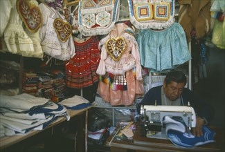 BOLIVIA, La Paz, Costume maker for Oruro Carnival. Man working on his sewing machine.