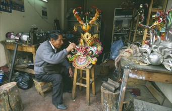 BOLIVIA, La Paz, Man in a workshop working on a mask.