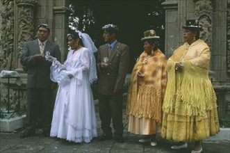 BOLIVIA, La Paz, Wedding in El Monticulo. Bride and guests standing under archway.