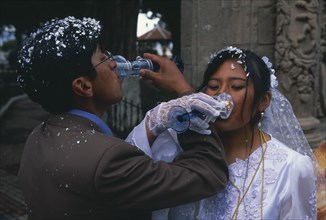 BOLIVIA, La Paz, Wedding in El Monticulo. Bride and Groom interlocking arms and drinking.