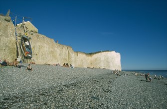 ENGLAND, East Sussex, Birling Gap, View across occupied peeble beach with boat leaning against a