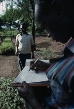 KENYA, Kamba Region, Forestry field assistant Joseph Wanjohia collecting Kamba dialect names and
