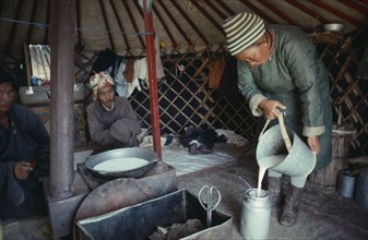 MONGOLIA, Gobi, South, Badamtsetseg pouring milk for tea inside yurt.
