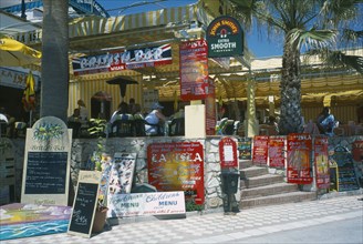 SPAIN, Andalucia, Benalmadena, Promenade with English restaurant and bar signs. People sat at