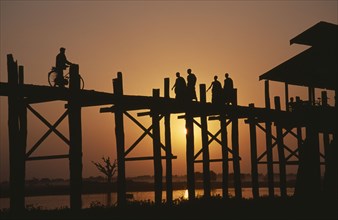 MYANMAR, Amarapura, U Bein Bridge near Mandalay at sunset with silhouetted figures of monks and
