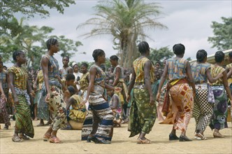 CONGO, Kimpese, Female dancers wearing colourful textiles at festival and watching crowd behind.