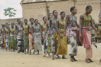 CONGO, Kimpese, Line of female dancers wearing colourful textiles at festival and watching crowd